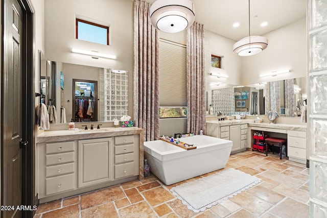 bathroom with a washtub, a high ceiling, and vanity