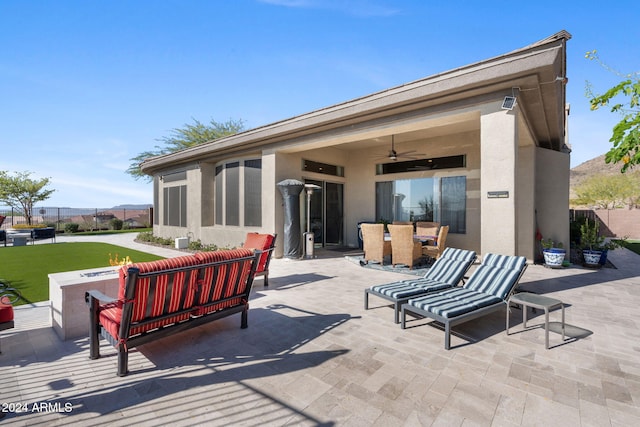 back of house with ceiling fan, a patio area, and an outdoor hangout area