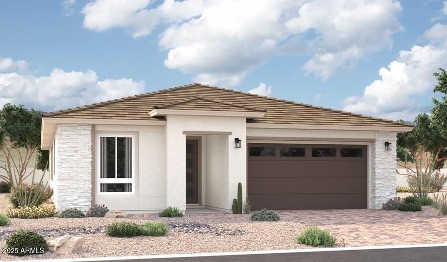 view of front of home featuring a garage, stone siding, decorative driveway, and stucco siding