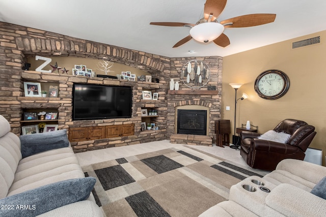 carpeted living room featuring ceiling fan and a stone fireplace