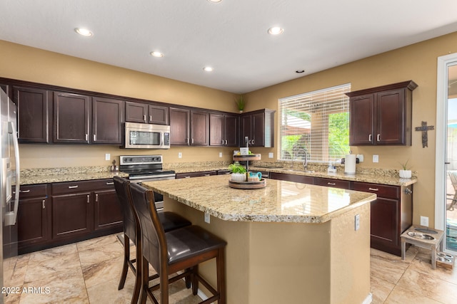 kitchen featuring dark brown cabinets, appliances with stainless steel finishes, a breakfast bar, and a kitchen island