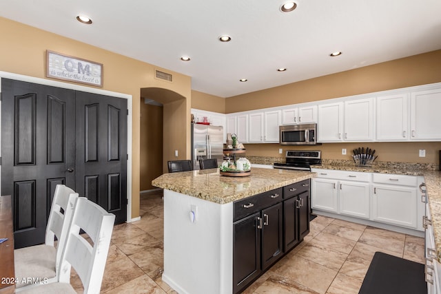 kitchen featuring light stone countertops, white cabinetry, appliances with stainless steel finishes, and a kitchen island