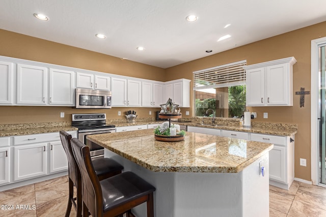 kitchen with a kitchen island, sink, stainless steel appliances, and white cabinetry