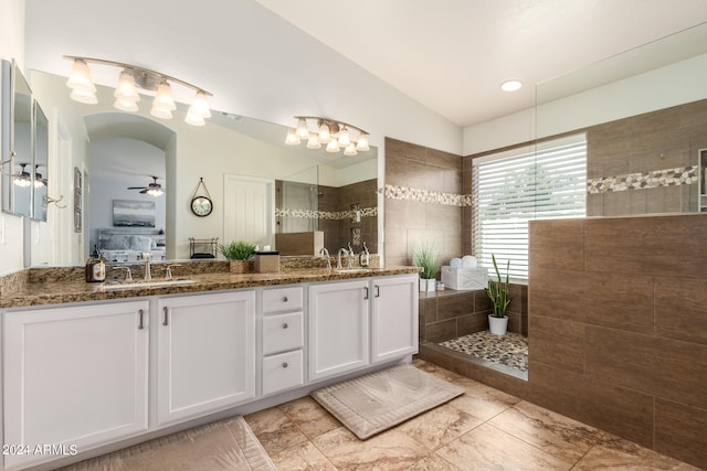 bathroom with a tile shower, vaulted ceiling, ceiling fan, and vanity