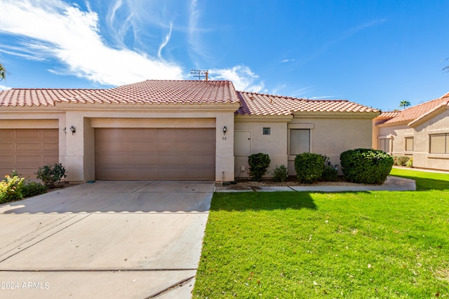 mediterranean / spanish-style house with a garage and a front lawn