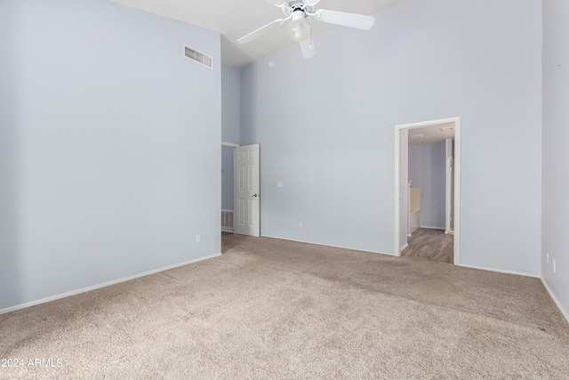 spare room featuring carpet floors, a towering ceiling, and ceiling fan