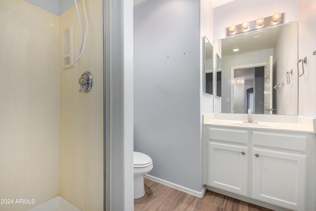 bathroom featuring toilet, an enclosed shower, vanity, and wood-type flooring