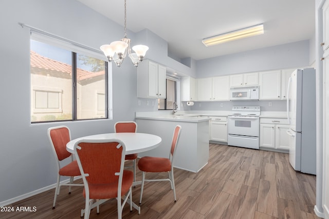 kitchen featuring pendant lighting, light wood-type flooring, a chandelier, white cabinets, and white appliances