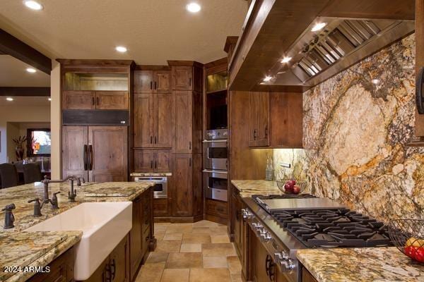 kitchen featuring stainless steel appliances, tasteful backsplash, light stone counters, and premium range hood