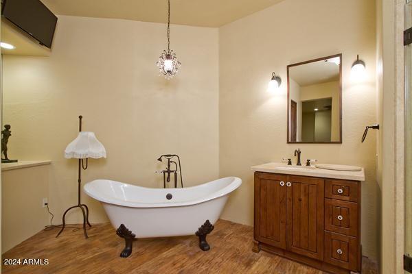 bathroom with hardwood / wood-style floors, a tub to relax in, and vanity