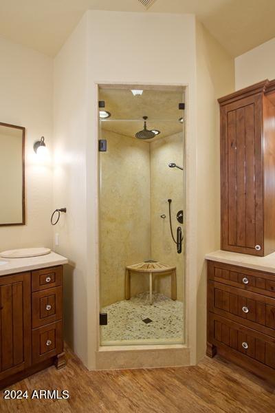 bathroom with hardwood / wood-style floors, a shower with door, and vanity