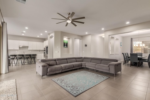 tiled living room with ceiling fan with notable chandelier