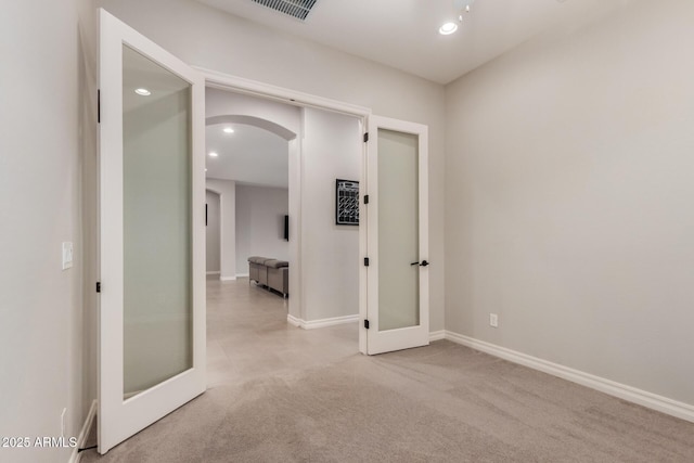 hallway with french doors and light colored carpet