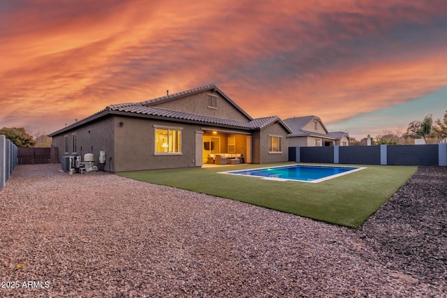 back house at dusk with a fenced in pool, a patio, outdoor lounge area, and cooling unit