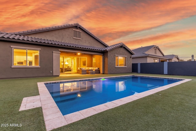 pool at dusk with a yard, an outdoor hangout area, and a patio