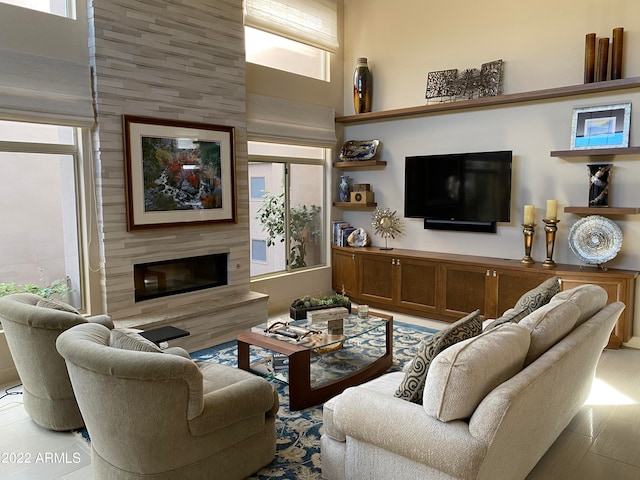 living room with a large fireplace, a towering ceiling, and light wood-type flooring