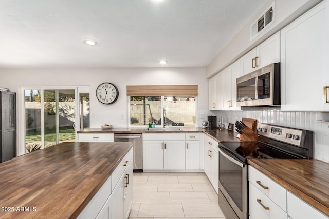 kitchen with white cabinets, stainless steel appliances, wood counters, and sink