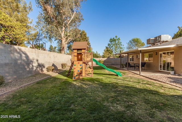 view of play area featuring a lawn, central air condition unit, and a patio