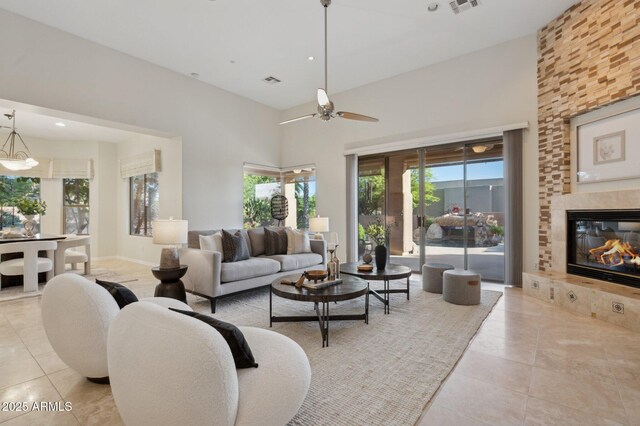11299 E Greythorn Dr, Scottsdale, AZ 85262 - living area with tile patterned flooring, a tiled fireplace, ceiling fan, and a high ceiling