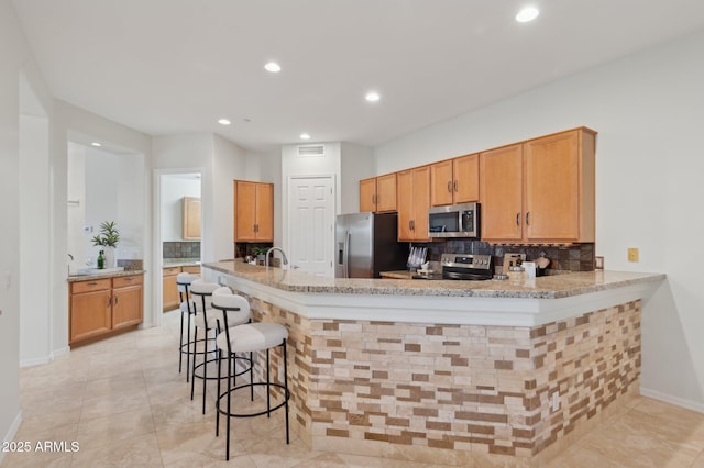 11299 E Greythorn Dr, Scottsdale, AZ 85262 - kitchen with stainless steel appliances, backsplash, recessed lighting, light stone countertops, and a breakfast bar