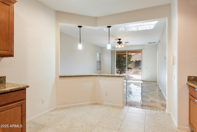 kitchen with hanging light fixtures, light stone counters, ceiling fan, and light tile patterned flooring