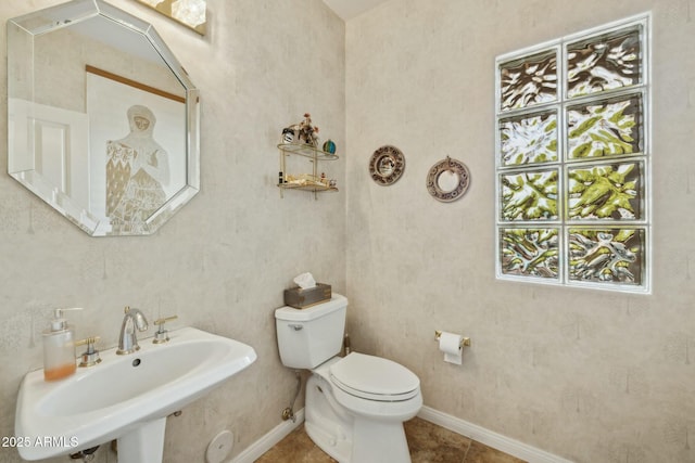 half bath with a sink, baseboards, toilet, and tile patterned flooring