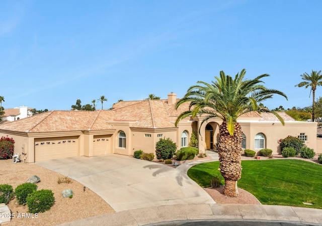 mediterranean / spanish house featuring a front lawn, a tiled roof, concrete driveway, stucco siding, and an attached garage