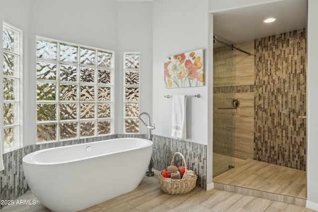 full bath with a soaking tub, tile walls, and tiled shower