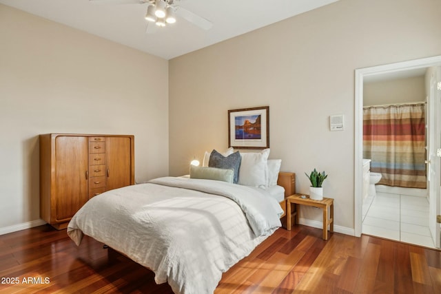 bedroom with connected bathroom, baseboards, and wood finished floors