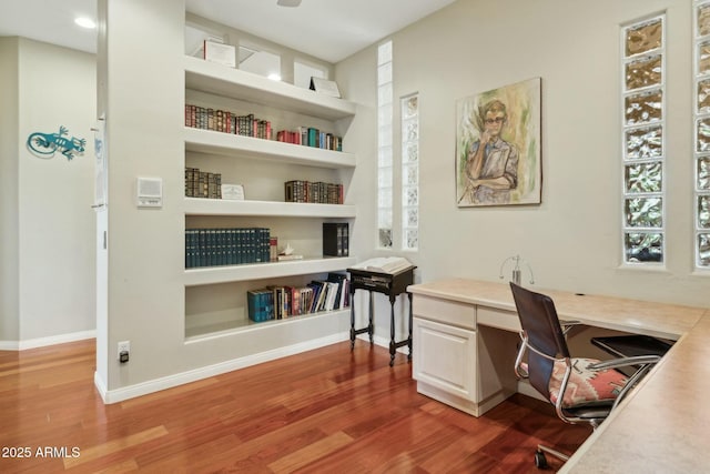 office featuring built in features, wood finished floors, and baseboards