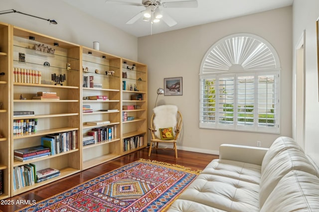 living area with baseboards, ceiling fan, and wood finished floors