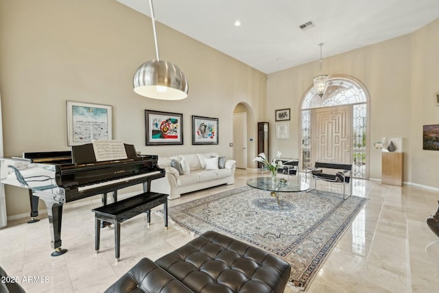 living area with visible vents, baseboards, a high ceiling, arched walkways, and marble finish floor