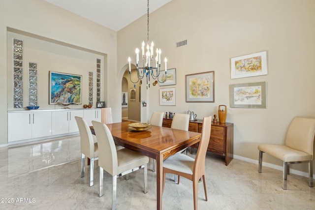 dining room featuring visible vents, a notable chandelier, marble finish floor, arched walkways, and baseboards