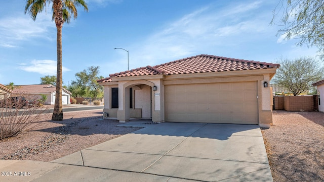 mediterranean / spanish-style house with a tile roof, stucco siding, concrete driveway, fence, and a garage