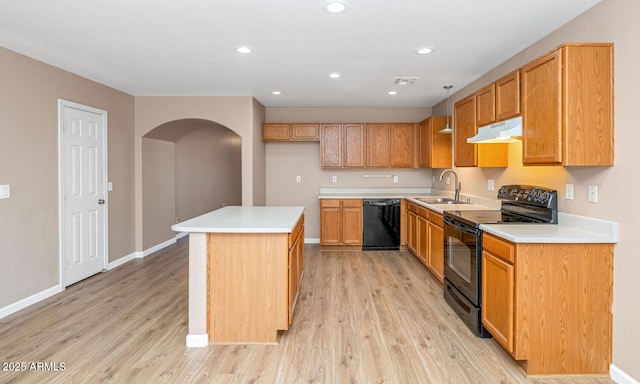 kitchen featuring arched walkways, under cabinet range hood, a sink, black appliances, and light wood finished floors