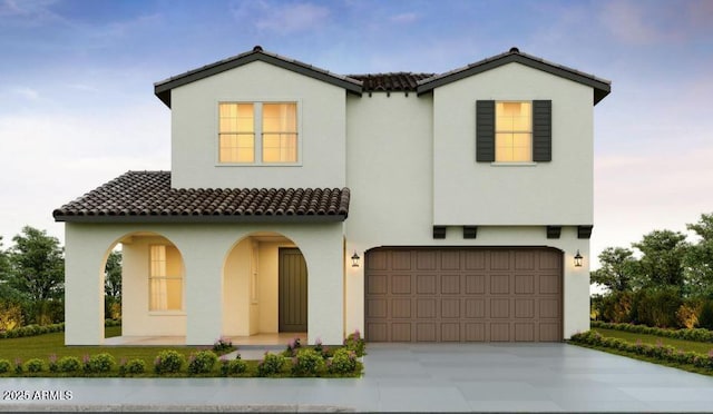 mediterranean / spanish house with driveway, a tiled roof, a garage, and stucco siding