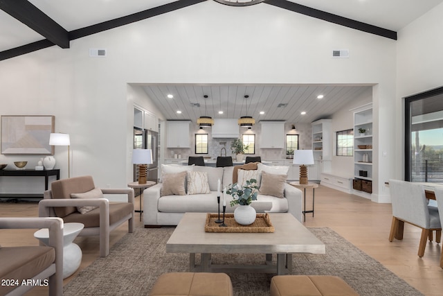 living room with light hardwood / wood-style floors, beam ceiling, and high vaulted ceiling