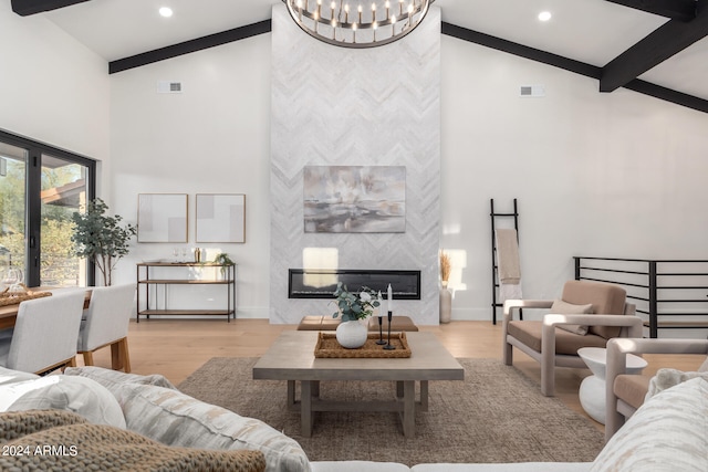 living room featuring high vaulted ceiling, a large fireplace, beamed ceiling, and light hardwood / wood-style flooring