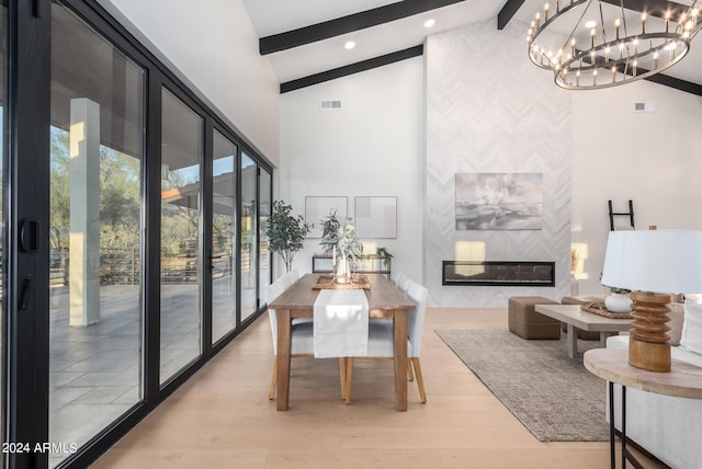 dining room featuring high vaulted ceiling, beamed ceiling, light hardwood / wood-style flooring, and a chandelier