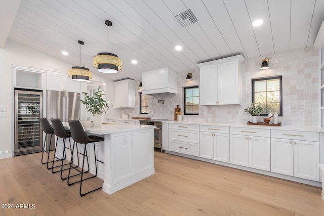 kitchen featuring stainless steel range, beverage cooler, light wood-type flooring, and white cabinetry