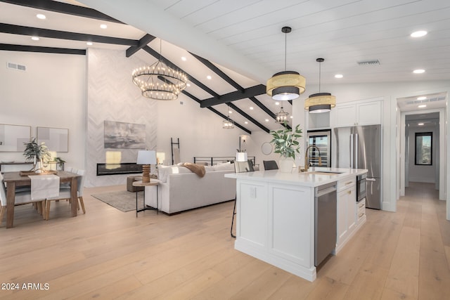 kitchen with appliances with stainless steel finishes, vaulted ceiling with beams, white cabinetry, and decorative light fixtures