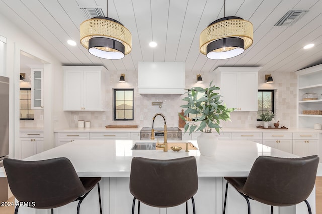 kitchen featuring white cabinetry, a center island with sink, and backsplash