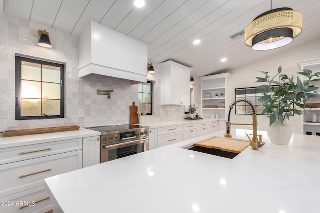 kitchen featuring tasteful backsplash, sink, white cabinets, hanging light fixtures, and stainless steel range