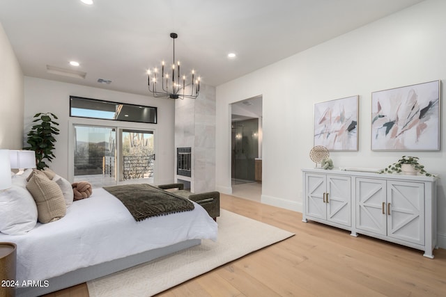 bedroom featuring light hardwood / wood-style floors, a high end fireplace, an inviting chandelier, ensuite bathroom, and access to outside