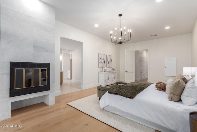 bedroom with light hardwood / wood-style floors, a fireplace, and a notable chandelier