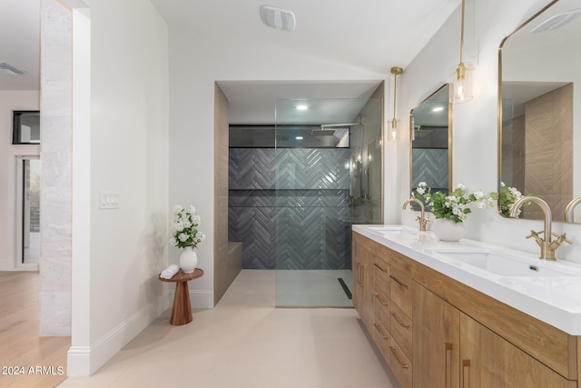 bathroom with tile walls, tiled shower, vanity, and tile patterned flooring