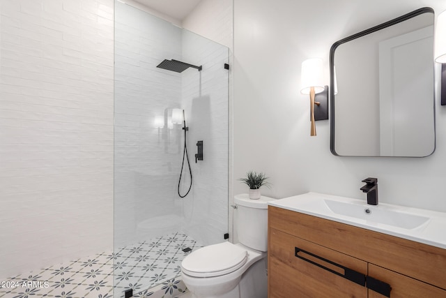 bathroom with a tile shower, vanity, and toilet