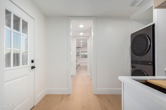 laundry room featuring light hardwood / wood-style floors and stacked washing maching and dryer