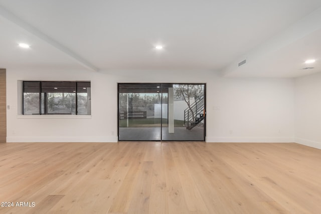 unfurnished living room with light hardwood / wood-style flooring and beam ceiling