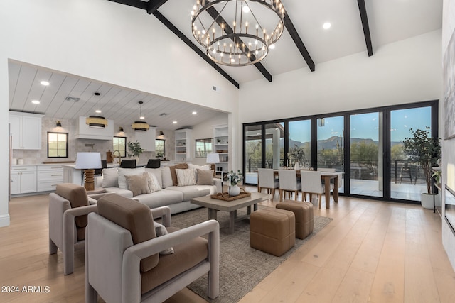 living room featuring a mountain view, beamed ceiling, high vaulted ceiling, an inviting chandelier, and light hardwood / wood-style floors